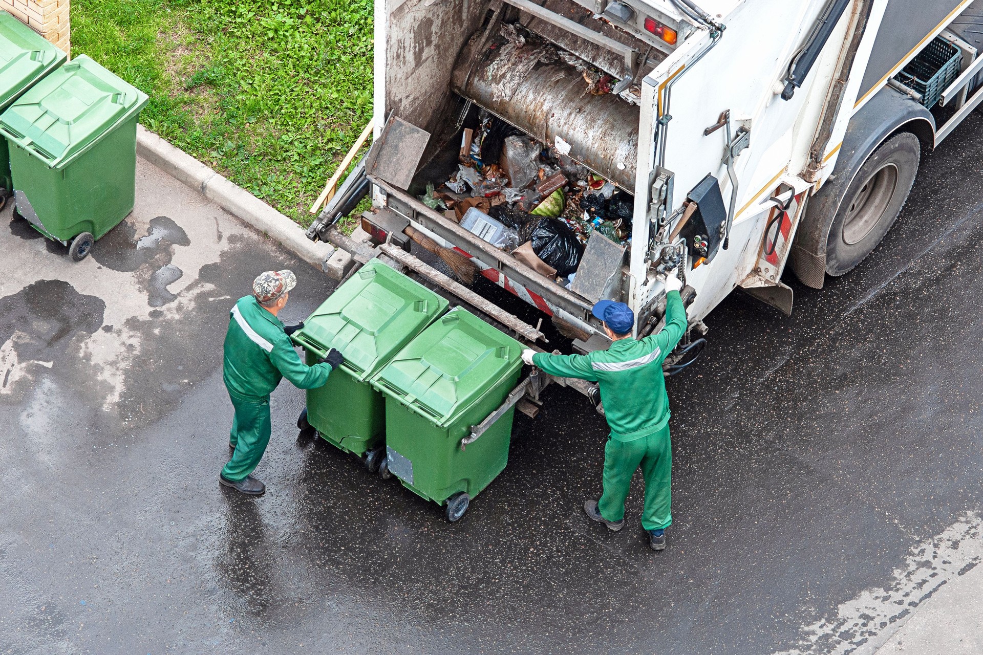 two workers loading mixed domestic waste in waste collection truck